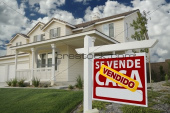 Vendido Se Vende Casa Spanish Real Estate Sign and House and Blue Sky with Clouds.