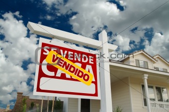 Vendido Se Vende Casa Spanish Real Estate Sign and House and Blue Sky with Clouds.