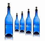Five blue glass bottles with water on a white