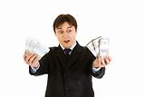 Surprised modern businessman holding money in his hand

