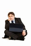 Bored businessman sitting on floor with laptop
