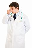 Stressed medical doctor holding fingers at noseband
