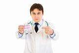 Serious medical doctor pointing finger at pack of pills 
