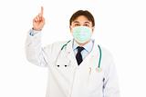 Medical doctor in mask pointing  finger up
