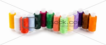Spools multi-colored threads located a wave isolated on a white background