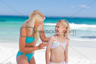 Mother applying sun cream on her daughter's back