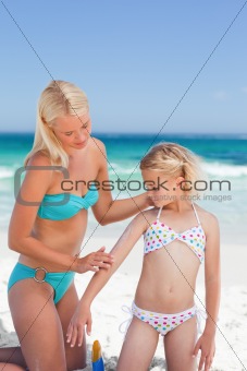 Mother applying sun cream on her daughter