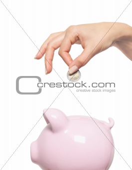 Hand putting money into the piggy bank isolated on white