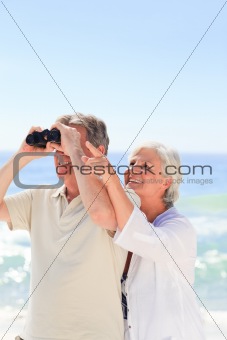 Senior couple bird watching at the beach