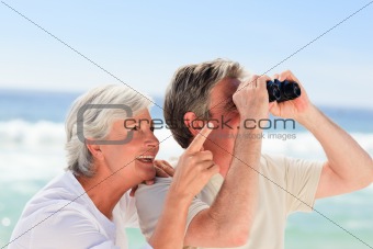 Senior couple bird watching at the beach