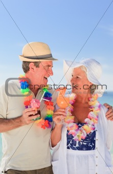 Elderly couple drinking a cocktail on the beach