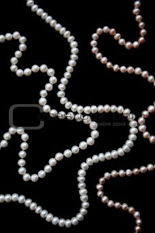 White and pink pearls on the black silk 