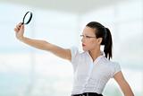 Business woman holding magnifying glass