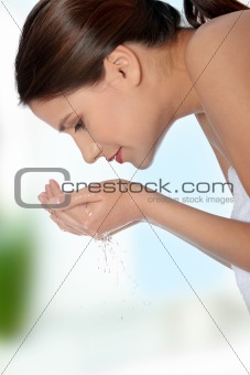 Young beautiful female washing her face