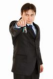 Serious young businessman holding keys in  hand
