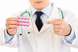 Medical doctor pointing finger on pack of pills. Close-up.
