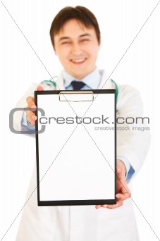 Smiling medical doctor holding blank clipboard in hands
