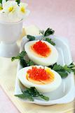 appetizer egg with red caviar on a white plate