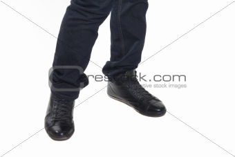 Man's feet in blue trousers and black shoes