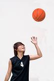 Asian female teen basketball player looking up at ball