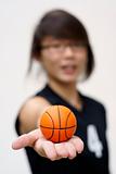 Asian teen holding tiny orange basketball in hand