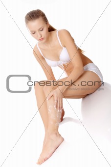 Applying moisturizer cream on the legs 