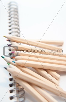 Set of color pencils on a binded white notepad
