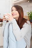 Young woman having coffee or tea in the kitchen 