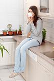 Young woman having coffee or tea in the kitchen 