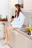 Young sad woman sitting on kitchen counter