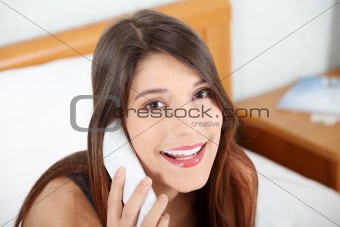 Pretty woman with phone sitting on bed