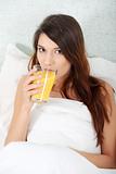Woman in bed drinking orange juice