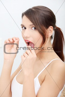 Beautiful young woman using dental floss