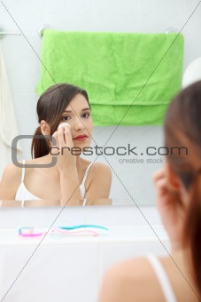 Young beautiful caucasian woman cleaning her face 