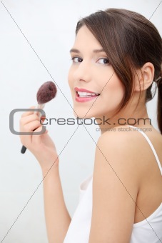 Portrait of attractive young adult woman applying blusher
