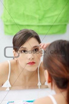 Young woman plucking her eyebrows