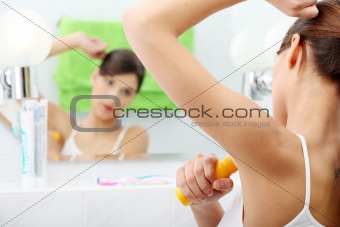 Young beautiful caucasian woman using deodorant