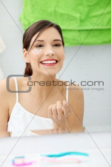 Beautiful woman applying cream on face