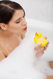 Woman taking a bath with yellow duck.