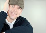 Smiling Man In Newsboy Hat Resting His Head On His Hand