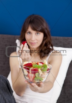 Girl on bed eating fruits