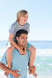Father having son a piggyback at the beach