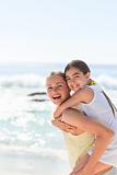 Mother having daughter a piggyback at the beach