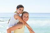 Mother having daughter a piggyback at the beach