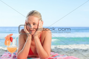 Pretty woman smiling on the beach with a cocktail
