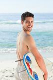 Handsome man beside the sea with his surfboard
