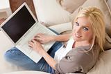 Young Blond Woman Using Laptop Computer At Home on Sofa