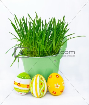 Colorful Easter eggs next to the bucket with the spring grass