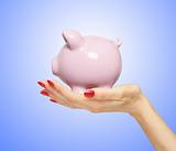piggy bank on woman hand over blue background