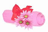 Twisted pink towel with red ribbon bow and pink flowers isolated